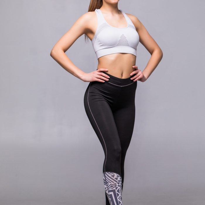 Full body of young cheerful smiling woman in sports wear, isolated over white background